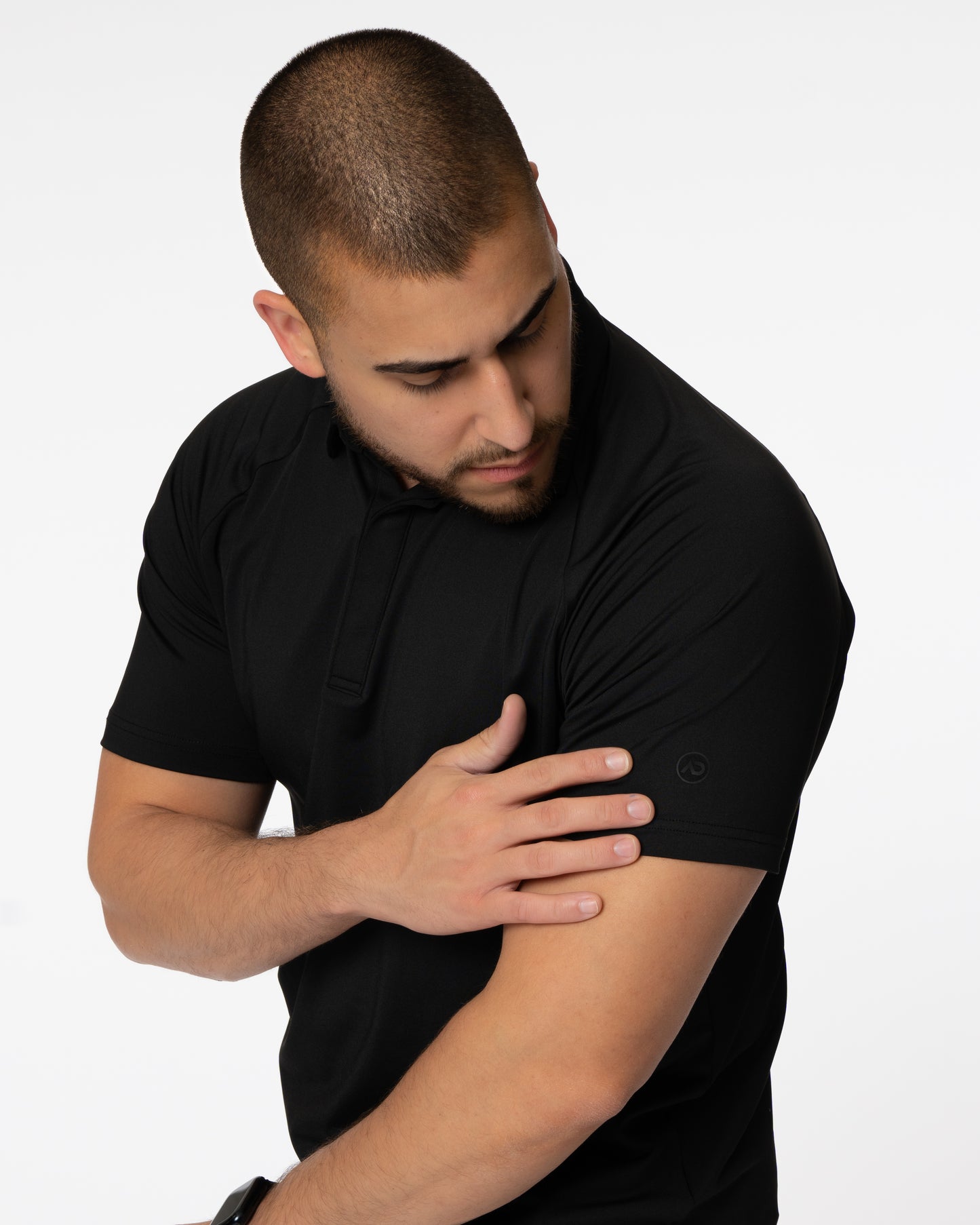 Man touching sleeve of black golf polo