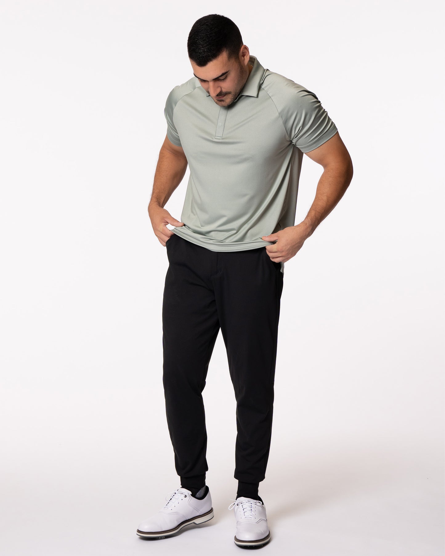 Man grabbing hem of green golf polo