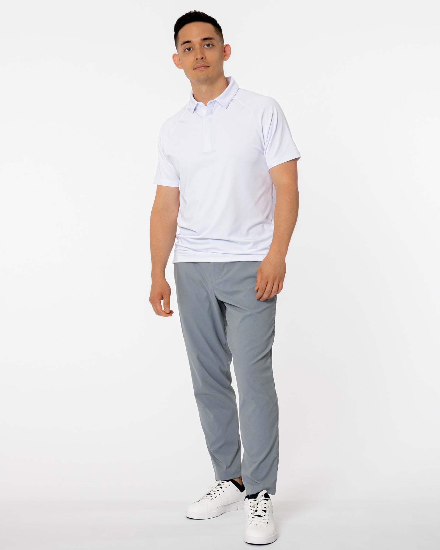 Man wearing white golf polo and gray pants