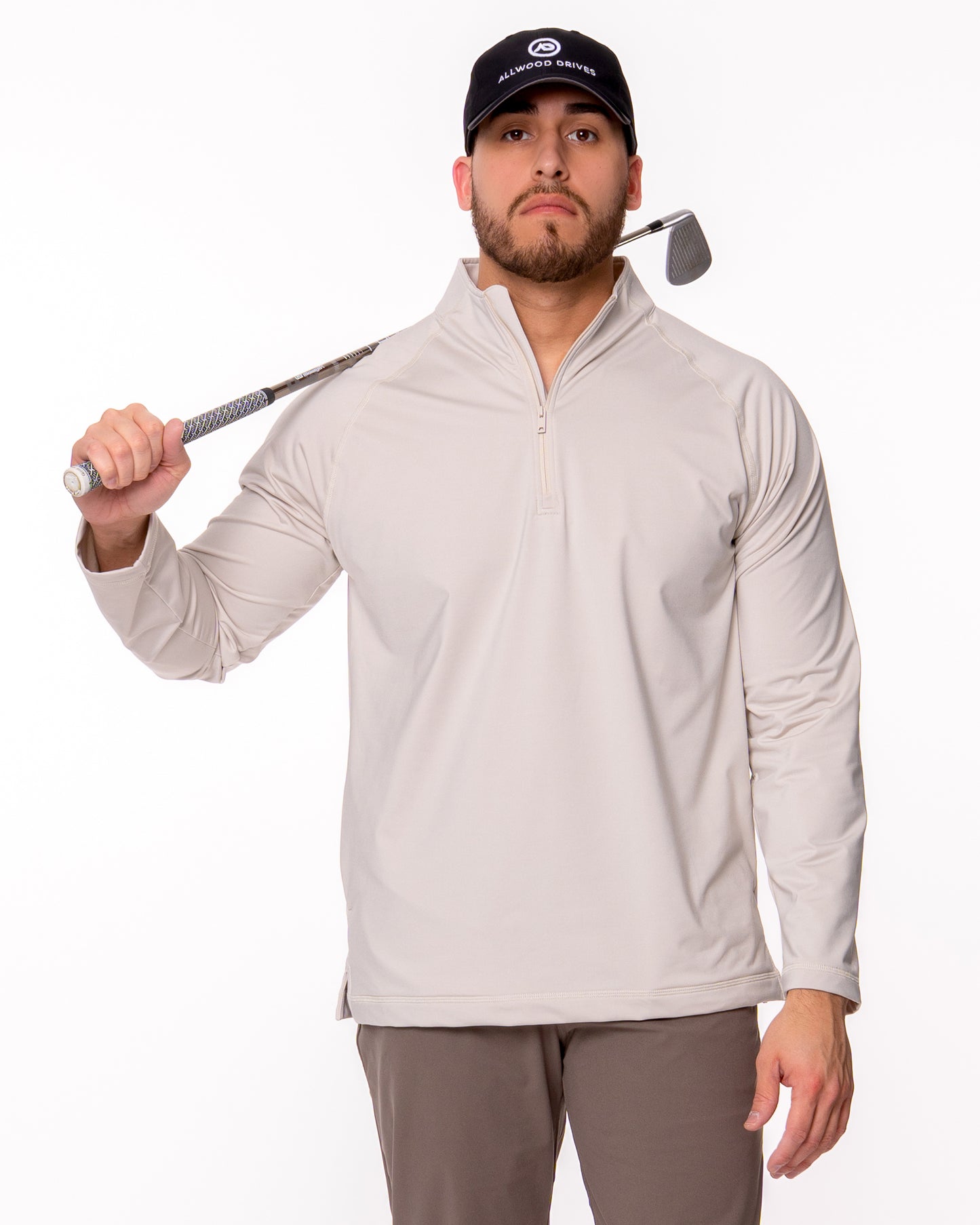 Man wearing beige quarter zip shirt holding a golf club